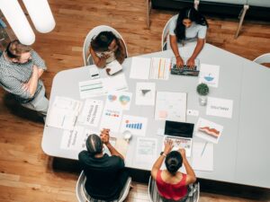 Marketing manager and 4 team members in a meeting looking at graphs